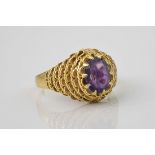 A vintage 18ct gold and amethyst ring, 1960s-70s, the oval cut amethyst claw set over pierced rope