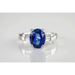 An 18ct white gold, sapphire and diamond ring, the central, oval cut sapphire weighing approximately