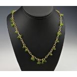 A 9ct gold and peridot opera length necklace, featuring clusters of briolette cut peridot along a