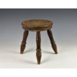 A 19th century wooden milking stool, with tripod turned legs, 9 3/8in. (24cm.) high.