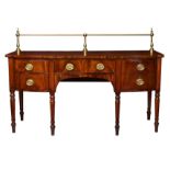 An early 19th century breakfront mahogany sideboard, the deep top with brass rail gallery to