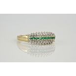A 9ct emerald and diamond three row ring, featuring 9 round cut emeralds to the centre of the band