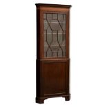 A George III style mahogany glazed floorstanding corner cupboard, 1920s, the dentil inlaid cornice