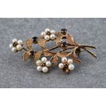 A 9ct yellow gold, garnet and seed pearl floral spray brooch, the floral detailing with garnet