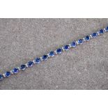 An 18t gold, sapphire and diamond line bracelet, the oval cut sapphires totalling approximately 11.
