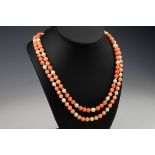 A coral and cultured pearl opera length necklace, with trios of round coral beads measuring