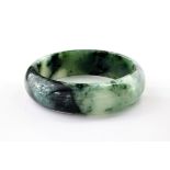 A contemporary jade bangle, of dark green and white marbled colouring and with a diameter of