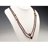 A dark ruby and 18ct gold opera length necklace, featuring a single strand of briolette cut
