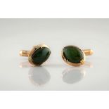 A pair of 9ct gold and green stone cufflinks, the cabochon green stones in oval, four claw settings.