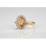 An 18ct yellow gold and blush sapphire ring, the central, oval cut 'blush' sapphire measuring