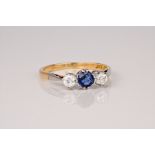 An 18ct white gold, diamond and sapphire trilogy ring, the central round cut sapphire of