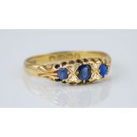 An 18ct yellow gold, sapphire and diamond boat ring, featuring 3 cushion cut sapphires of deep,