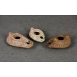 Three Roman terracotta oil lamps, two of teardrop form with peaked handle and raised line