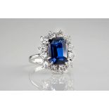 An 18ct white gold, sapphire and diamond cluster ring, the central, emerald cut sapphire of deep,