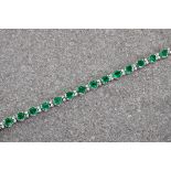 An 18ct white gold, emerald and diamond bracelet, the oval cut emeralds measuring approximately 8.