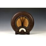 A vintage EKCO AD75 circular bakelite radio, brown bakelite, raised on bracket style feet, paper