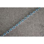 An 18ct white gold, blue topaz and diamond line bracelet, featuring approximately 12.0ct of bright