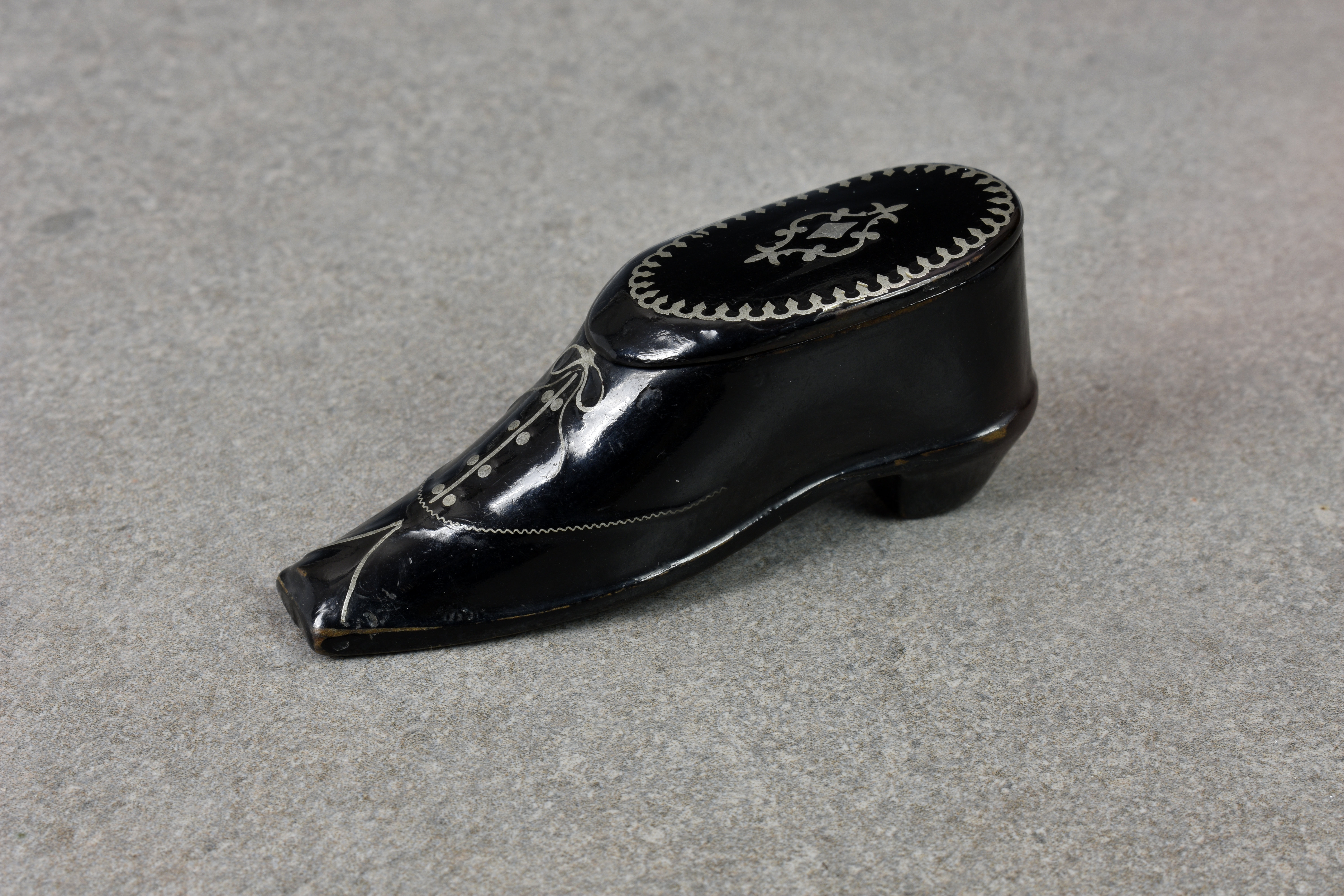 An elegant Victorian papier maché snuff box fashioned as a shoe, having ornate pewter inlay,