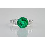 An impressive 18ct white gold, emerald and diamond ring, the central, round cut emerald weighing