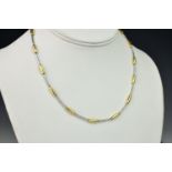 A two tone 18ct gold and diamond necklace, consisting of articulating white and yellow gold bars,