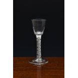 A mid-18th century airtwist wine glass, c.1760, the round funnel bowl with basal fluting, on a