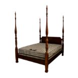 A George III style mahogany four poster bed, with reeded, foliate and swag carved columns over a