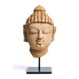 A BUFF SANDSTONE HEAD OF A JINA, WESTERN INDIA, 11TH/12TH CENTURY