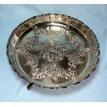 A silver circular fruit dish with scalloped edge and repousse decoration, raised on 3 paw feet,