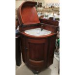 A Victorian pitch pine case corner unit fitted with a ceramic washbasin, hinged lid and door, in the