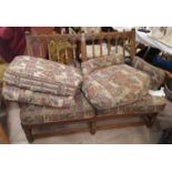 An Ercol country style two seater settee with stick back floral tapestry upholstery