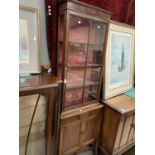 An Edwardian full height thin display cabinet with glazed top cupboard and door bellow (one back leg