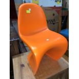 A mid century style moulded child's chair in orange