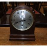 An oak cased mantel clock with arch top, reeded decoration and silvered dial