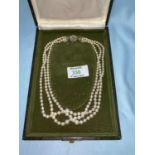 A triple strand necklace of graduating cultured pearls, the white metal gem set clasp stamped '750'