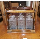 An Edwardian oak tantalus with 3 bottles