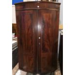 A Georgian bow front inlaid mahogany corner cupboard