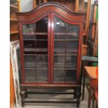 An early 20th century mahogany display cabinet with 2 doors and dome top, on turned bulbous legs (