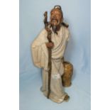 A large Chinese stoneware figure of a man with staff and water jar, having crackle glaze robes and