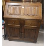 An oak reproduction bureau with cupboard under, carved linen fold decoration