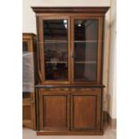 An Edwardian full height bookcase with ebonised mouldings, twin glazed doors over 2 drawers and 2