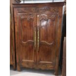 An 19th century French Provincial carved chestnut armoire enclosed by 2 panelled and brass studded