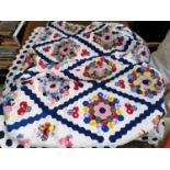 A double size patchwork quilt, hand sewn, formed from hexagonal pieces lined with white cotton