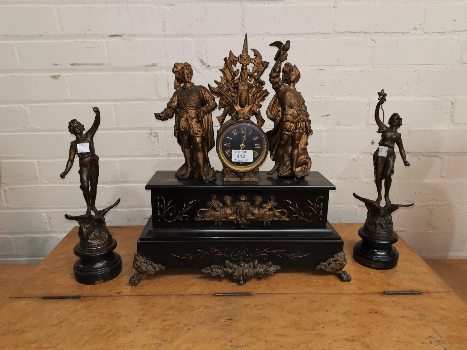 A 19th century clock garniture in black marble and gilt, the clock surmounted by 2 figures, with