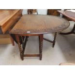 An early 20th century oak drop leaf occasional table with carved oval top, on barley twist legs