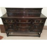 A 1930's oak sideboard of 5 drawers and 2 cupboards, geometric moulded decoration