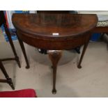 A reproduction crossbanded figured walnut fold over demi-lune card table with green baize lining