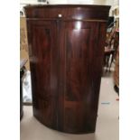 A Georgian bow front inlaid mahogany corner cupboard