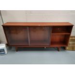 A 1960's teak sidecabinet with open shelves and sliding glass doors; a 1960's 4 height chest of