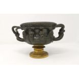 A 19th century bronze 2-handled urn, decorated with bearded heads in relief, gilded pedestal foot,