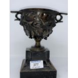 A 19th century bronze 2 handled cup with relief trailing ivy branches, on ebonised base, overall